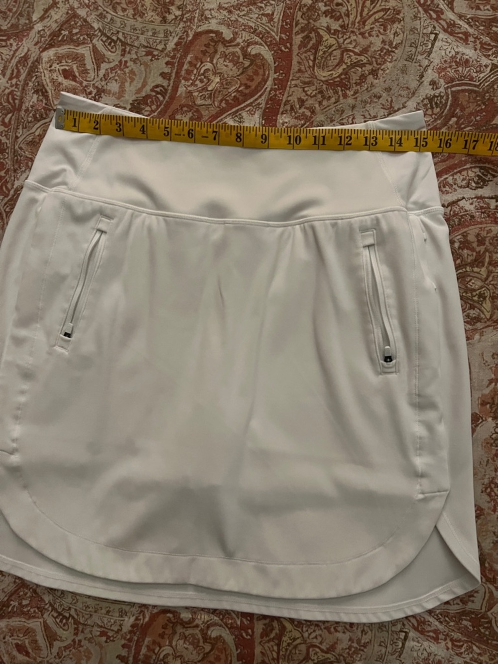 Athleta brand "Fairway" 18” white golf skort with front zip pockets.
